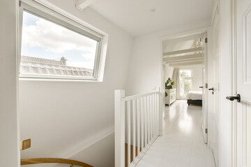 A well-lit modern hallway showcasing clean lines, white walls, and natural light from a large window. Minimalist design creates a spacious feel.