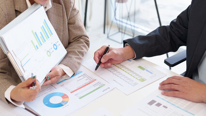 Senior business professionals discussing financial growth strategies while reviewing performance charts and reports in a modern office.