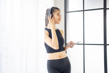 Fitness asian woman using smart phone and headphones Enjoy listening to music. Female with headphones smart phone after workout