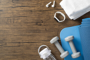 Fitness essentials including a mat, dumbbells, towel, watch, and earbuds on wood surface