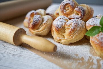 sweet buns with powdered sugar and rolling pin on a wooden table