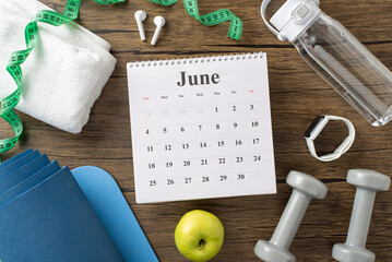 Flat lay of fitness tools including dumbbells, a calendar, and measuring tape for workouts