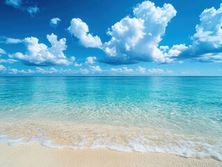Obraz premium Serene turquoise ocean meets pristine sandy beach under a vibrant blue sky dotted with fluffy white clouds creating a tranquil summer paradise