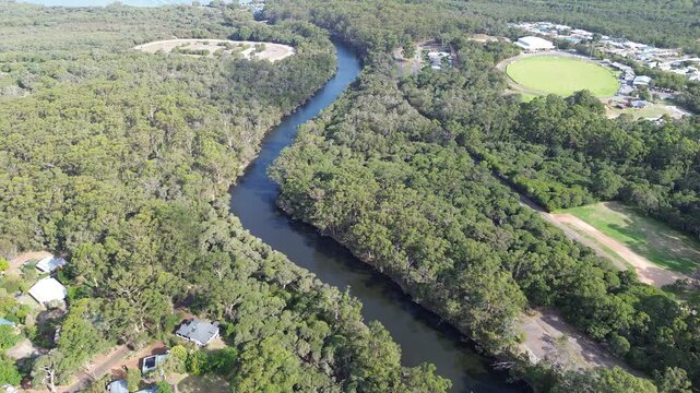Smooth Aerial view of the meandering  Denmark River, Western Australia, Landscape, with lush forest, tall karri trees, a winding country road, horse racing and sports field. 4k Drone footage 