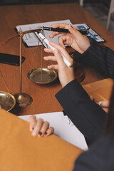 Attractive young lawyer in office Business woman and lawyers discussing contract papers with brass scale on wooden desk in office. Law, legal services, advice, Justice and real estate concept.
