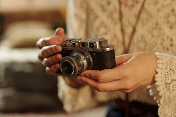 Hands holding vintage film camera, focusing on intricate details and craftsmanship. Background appears slightly blurred, enhancing visual focus on camera © pressmaster