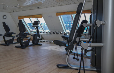 Obraz premium Moderne Fitnessgeräte und Kraftmaschinen in Sportstudio auf Kreuzfahrtschiff - Modern cardio and weight equipment in fitness center gym onboard cruiseship cruise ship liner