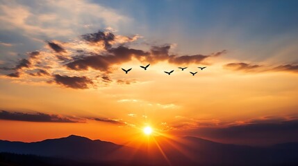 Obraz premium Majestic sunset landscape with a flock of birds flying across the orange sky and silhouette mountains : Generative AI