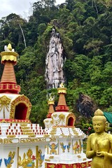 Fototapeta premium Golden Buddha Statue and Ornate Stupas with Carved Mountain Guardian