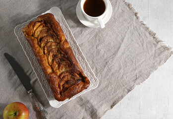 Apple pie and a cup of coffee on the linen napkin on the table in hard light. top view, healthy breakfast, copy space