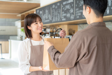 Obraz premium カフェの女性店員とテイクアウトをするお客