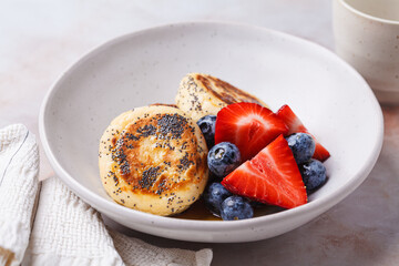 Cottage cheese pancakes with poppy seeds, syrup and berries.