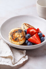 Cottage cheese pancakes with poppy seeds, syrup and berries.