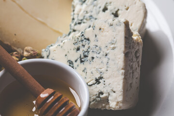 Cheese plate for party with honey, nuts and berries.