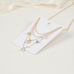 White jewelry display card holding three layered gold and silver necklaces with intricate beadwork. Women goods and female goods showcase elegance, beauty, and luxury for popular women product.