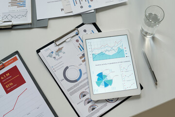 Top view background image of clipboard and statistics data charts on tablet screen, copy space