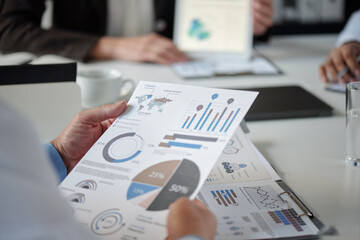 Close up of unrecognizable doctor holding data report with statistics charts while sitting at...