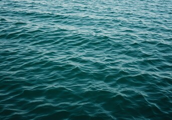 Obraz premium extured ocean surface with golden highlights reflecting the light. The waves create a beautiful, natural pattern across the water.