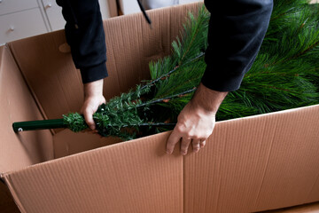 Male adult packing artificial Christmas tree in cardboard box