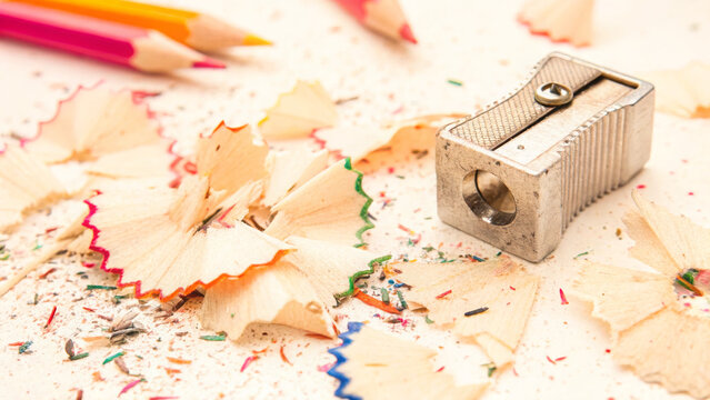 A close-up of a pencil sharpener surrounded by colorful pencil shavings, color pencil and sharpener - Powered by Adobe