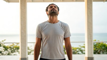 Fototapeta premium Yoga for beginners balance concept. A man stands peacefully with eyes closed, enjoying a moment of relaxation by the sea.