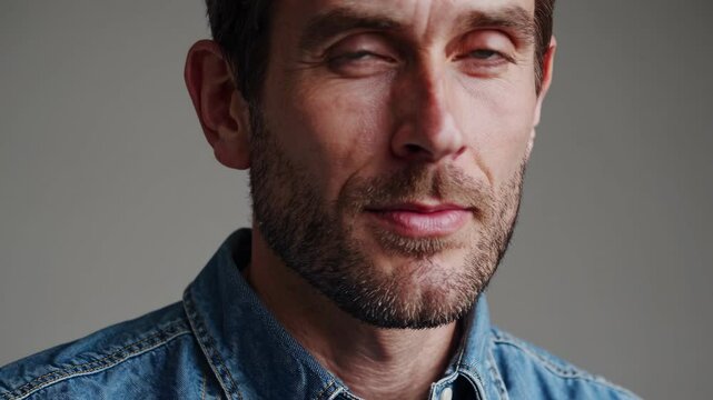 A man displays his style with a close-up view highlighting his beard and denim shirt. The focus is on his facial features and the texture of the clothing.