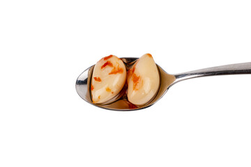Two cloves of marinated garlic in a spoon, isolated on a white background. Garlic in oil lies in a spoon.