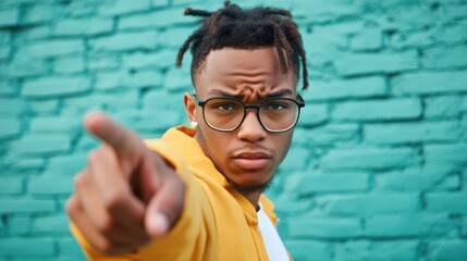 Young Man Points Finger Brick Wall Background