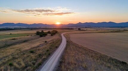 Fototapeta premium Stunning aerial view of a scenic countryside road winding through golden fields at sunset : Generative AI