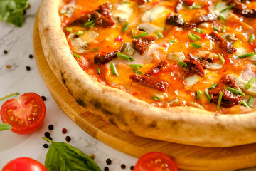Appetizing, fresh pizza is on the table. Food from an Italian restaurant. Cooking pizza. Pizza ingredients.