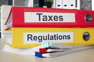 Folders with labels taxes and regulations. Financial compliance and legal obligations.
