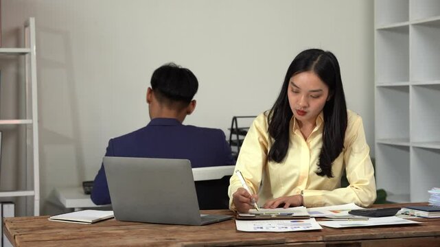 Workplace Harmony: A dynamic scene unfolds in a modern office, where two colleagues are engrossed in their respective tasks. A woman, her face illuminated with focus.