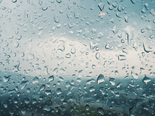 Rain droplets on a window overlooking a cloudy landscape during a rainy afternoon