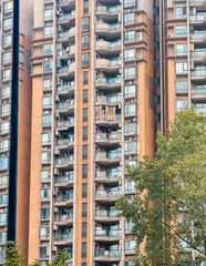 Fototapeta premium Modern residential building showcasing balconies and air conditioning units in a bustling urban area.