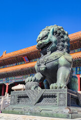 A giant bronze lion statue in front of Taihe Gate in the Forbidden City, Beijing. The Plaque written in Chinese is the name of the building, which means 