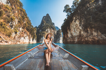 Traveler asian woman relax and travel on Thai longtail boat in Ratchaprapha Dam at Khao Sok...