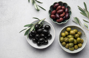 Black, green and kalamata olives with olive branches on marble background
