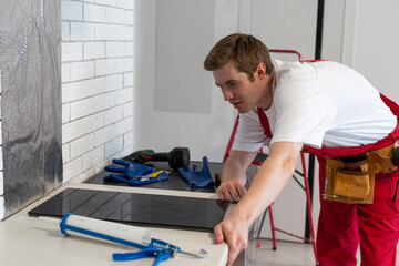 craftsman installs hob in kitchen. Household Appliance Installation Services Concept
