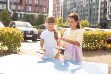 Kid playing table tennis outdoor with family