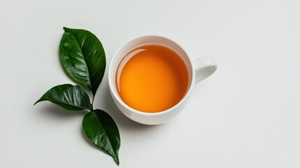 A white mug holding tea with leaves beside it