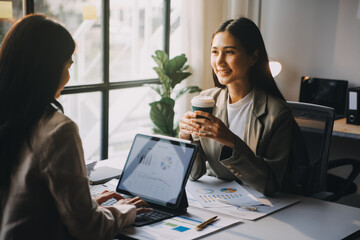 Two young Asian business woman talk, consult, discuss working with new startup project idea presentation analyze plan marketing and investment in the office.