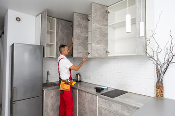 Worker installing door of cabinet in kitchen