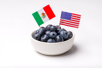 Bowl of Blueberries in a White Bowl on a White Background with Flags of USA and Mexico