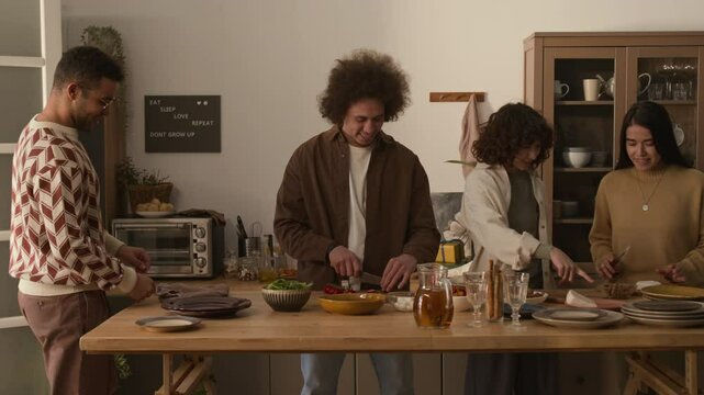 Group of four diverse friends talking and cooking together, preparing for dinner party at modern apartment