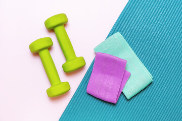 Green dumbbells, purple and mint resistance bands, and a teal yoga mat, perfect for fitness and wellness content. Home workout setup