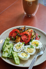 Bowl with boiled egg, fried eggplant and tomato salad, cucumber and black sesame.	

