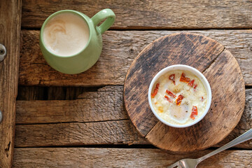 Portion baked eggs with cheese on a board on a wooden table. 