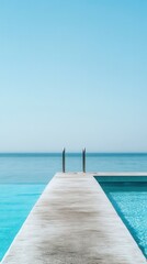 Obraz premium Tranquil Infinity Pool Overlooking Calm Sea Under Clear Blue Sky in Summer Resort Setting Ideal for Relaxation and Getaway