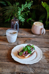 toast with melted cheese, fried bacon, sun-dried plums and parsley. homemade bread. Top view. Wooden background	
