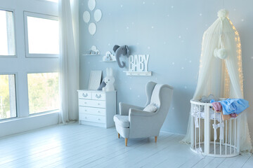 Stylish skandi interior of newborn baby room with bed, grey armchair and wooden dresser with toy and picture. Decor children room with furniture. Crib in a modern nursery room. Baby cot with canopy © stock_studio